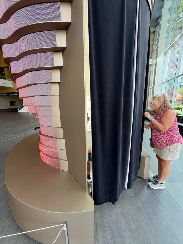 You stick your head in behind the screens and a camera scans your face to project it