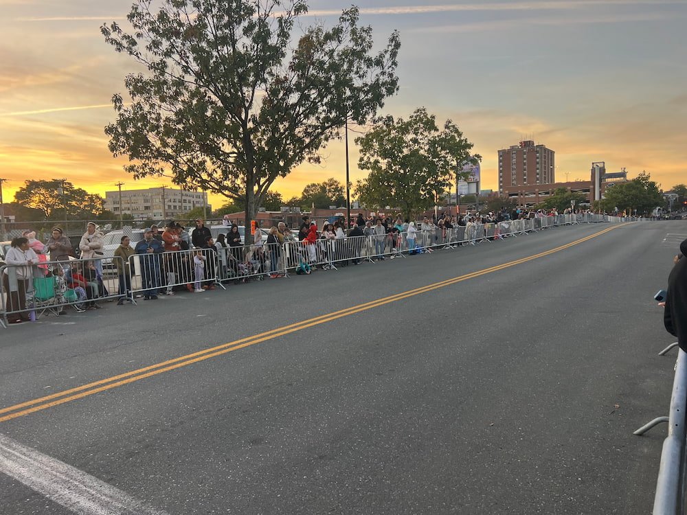 People lining the start pf the parade as the sun sets
